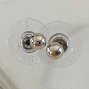 May include: Two silver earring backs with a clear plastic backing. The backs are labeled "Small" and "Big".