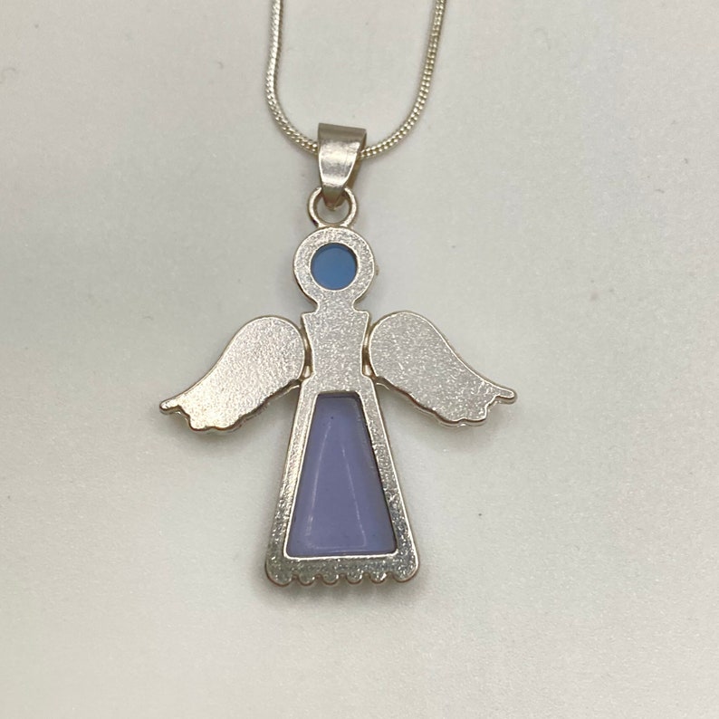 Op de afbeelding: Zilveren engel hanger ketting met een lichtblauwe en paarse steen. De engel heeft vleugels en een jurk.