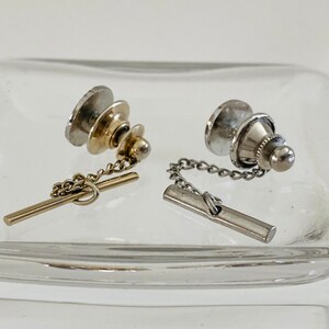 May include: Two tie tacks with chains. One is gold and the other is silver.