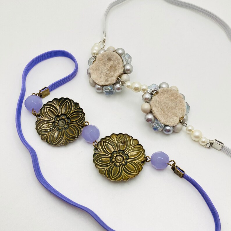 May include: A purple headband with two gold floral embellishments and a section of white and gray beaded flowers.