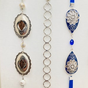 May include: Three silver chains with pendants. The chains are made of linked circles. The pendants are silver with blue enamel and intricate designs. The pendants are shaped like teardrops and have a floral pattern.