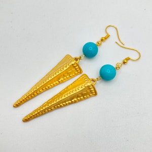 May include: Gold earrings with turquoise blue beads and a textured, pointed design.