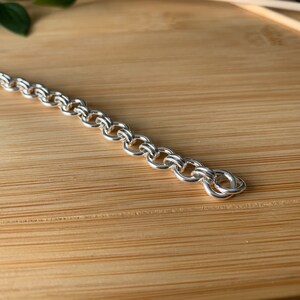 Puede incluir: Un brazalete de cadena de plata con un dise&ntilde;o delicado e intrincado. La cadena est&aacute; hecha de peque&ntilde;os c&iacute;rculos unidos que crean un aspecto suave y fluido.