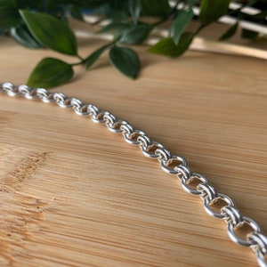 Puede incluir: Un collar de cadena de plata con un dise&ntilde;o de doble eslab&oacute;n.