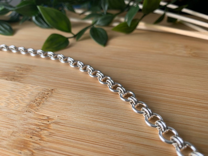 Puede incluir: Un collar de cadena de plata con un dise&ntilde;o de doble eslab&oacute;n.