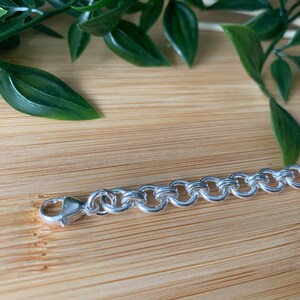 Puede incluir: Un brazalete de cadena de plata con cierre de mosquet&oacute;n. La cadena est&aacute; hecha de eslabones ovalados entrelazados.