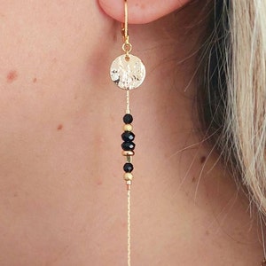 May include: Gold dangle earrings with a hammered circle charm and black beads.