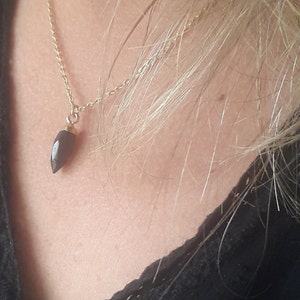 Peut inclure: Un collier en chaîne dorée avec un pendentif en pierre précieuse noire en forme de larme.