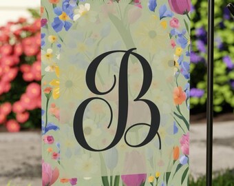 Peut inclure: Un drapeau de jardin avec un motif floral et une grande lettre noire "B". Le drapeau présente une variété de fleurs colorées, dont des fleurs roses, jaunes et bleues, sur un fond vert clair. Il est affiché sur un support en métal noir.