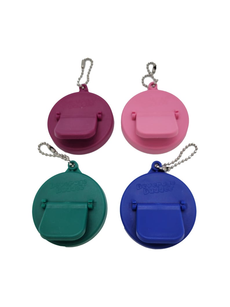 May include: Four round bottle stoppers with a flip-top lid and a keychain. The stoppers are in pink, purple, green, and blue.