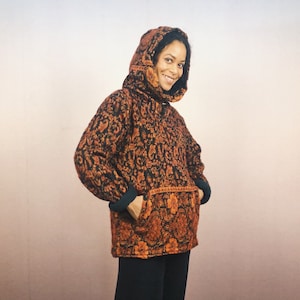 Könnte beinhalten: Ein schwarzer und orangefarbener Kapuzenpullover mit einem Blumenmuster. Der Pullover hat eine Kapuze mit Kordelzug und zwei Taschen.