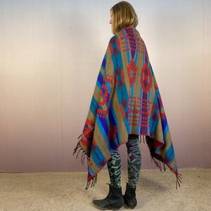 May include: A brown, blue, red, and purple patterned blanket with fringe. The blanket is draped over a person's shoulders.