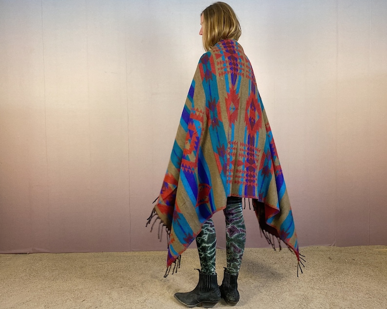 May include: A brown, blue, red, and purple patterned blanket with fringe. The blanket is draped over a person's shoulders.