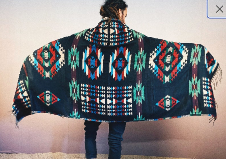 May include: A black hooded blanket with a colorful geometric pattern. The pattern features red, blue, green, and white colors. The blanket has fringe on the edges.