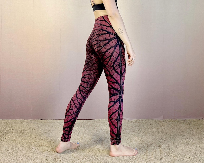 May include: Red and black patterned leggings with a leaf design. The leggings are form-fitting and have a high waist.