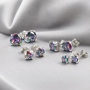 May include: Three pairs of round stud earrings featuring iridescent, multi-colored stones set in silver-toned metal prongs. Each pair varies in size, showcasing a spectrum of vibrant colors including purple, green, and blue hues within the faceted stones.