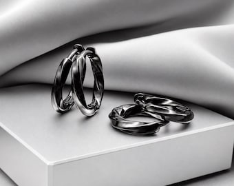 May include: A set of four polished black hoop earrings with a twisted, rope-like texture. Two earrings are positioned upright, while the other two are lying flat, showcasing the reflective metallic surface and the circular design of the jewellery.