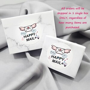 two white boxes with a marbled texture, each with a sticker that says "Happy Mail" and includes a heart and an envelope. The text above the boxes states that all orders will be shipped in a single box, regardless of how many items are purchased.
