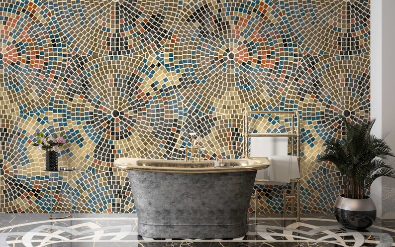 May include: A freestanding bathtub with a gray exterior and gold trim sits in a bathroom with a mosaic tile wall. The wall is made of small, colorful tiles arranged in a circular pattern. A gold metal towel rack is on the right side of the image.