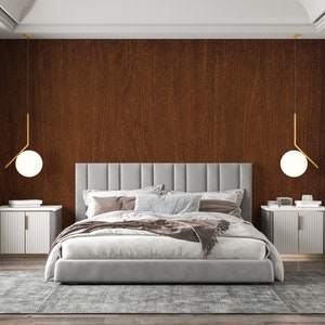 May include: A gray upholstered bed with a white duvet and throw blanket, two bedside tables with white drawers, and two gold pendant lights with white globe shades. The bedroom has a wood wall paneling and a gray rug.