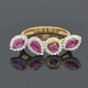 May include: A gold ring featuring a series of pink gemstones and small white diamonds. The ring's design includes marquise and round-cut stones, creating a floral or leaf-like pattern. The ring is displayed on a reflective surface.