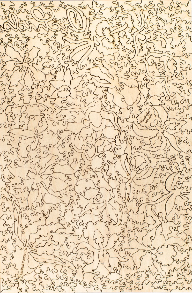 May include: A laser-cut wooden jigsaw puzzle featuring a floral design with intricate details. The puzzle is made of natural wood and has a light brown color. The puzzle is called "Handcrafted with Love".
