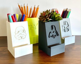 May include: A set of four desk organizers in white, neon green, and black. Each organizer features a Star Wars character design: Stormtrooper, Grogu, Darth Vader, and Mandalorian. The organizers hold pencils, markers, and a small succulent.