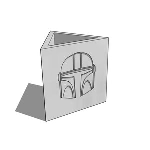 May include: A gray triangular pencil holder with a cutout of a Mandalorian helmet.