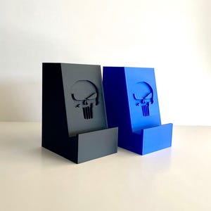 May include: Two phone stands, one black and one blue, with a skull design.