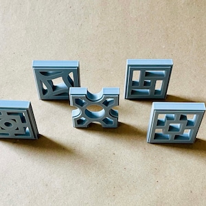 Puede incluir: Cinco baldosas de hormigón grises con diferentes patrones geométricos. Las baldosas están dispuestas en forma de cuadrado, con la baldosa central teniendo un patrón circular.