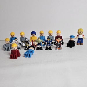 May include: A collection of 15 small plastic figurines, mostly depicting construction workers wearing yellow hard hats. There are also a few other figures, including a police officer, a firefighter, and a boy wearing a red shirt. The figures are all about 5 cm tall.