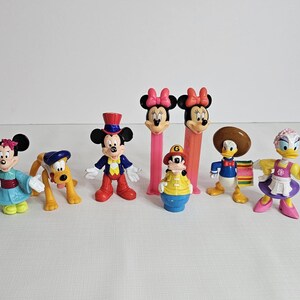 K&ouml;nnte beinhalten: Ein Set mit neun Disney-Charakterfiguren, darunter Mickey Mouse, Minnie Mouse, Donald Duck, Goofy, Pluto und andere. Die Figuren sind aus Kunststoff und bunt.
