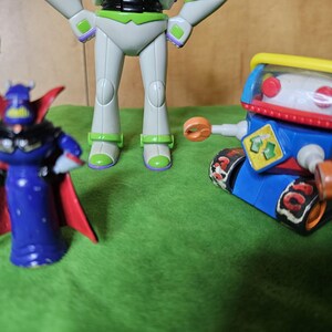 May include: A set of three toy figures, including a blue and red robot with a yellow visor, a white and green space ranger figure, and a purple and red villain figure with a cape.