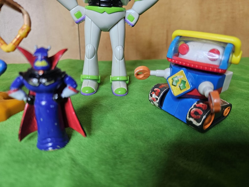 May include: A set of three toy figures, including a blue and red robot with a yellow visor, a white and green space ranger figure, and a purple and red villain figure with a cape.