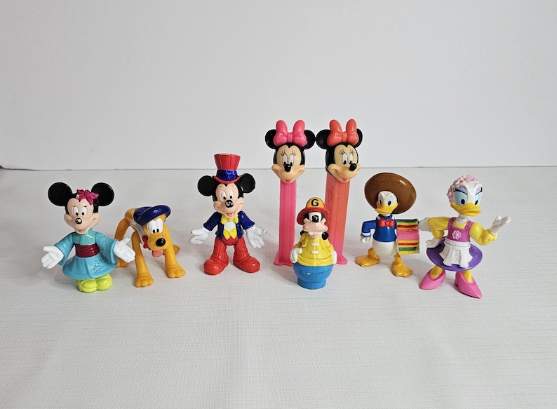 K&ouml;nnte beinhalten: Ein Set mit neun Disney-Charakterfiguren, darunter Mickey Mouse, Minnie Mouse, Donald Duck, Goofy, Pluto und andere. Die Figuren sind aus Kunststoff und bunt.
