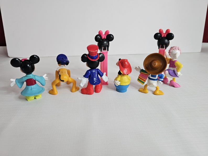 K&ouml;nnte beinhalten: Ein Set mit acht kleinen Disney-Figuren aus Plastik. Die Figuren umfassen Mickey Mouse, Minnie Mouse, Donald Duck, Goofy, Pluto und Daisy Duck. Die Figuren sind alle in verschiedenen Posen und sind bunt.