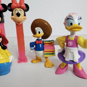K&ouml;nnte beinhalten: Eine Sammlung von Disney-Figuren, darunter Mickey Mouse, Minnie Mouse, Donald Duck und Daisy Duck. Die Figuren sind aus Kunststoff und bunt.