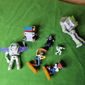 May include: A collection of six toy figures from the Toy Story franchise. The figures include Buzz Lightyear, Woody, and Emperor Zurg. The figures are made of plastic and are in good condition.