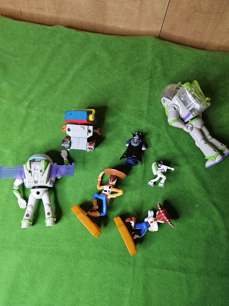 May include: A collection of six toy figures from the Toy Story franchise. The figures include Buzz Lightyear, Woody, and Emperor Zurg. The figures are made of plastic and are in good condition.