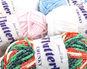 May include: Close-up of several balls of chunky yarn in various colors, including white, pink, blue, and a multi-colored mix of green, red, and white. Each ball is labeled with "Flutterby CHUNKY" and "James C. Brett".