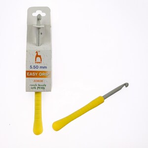 May include: A yellow and gray crochet hook with an easy grip handle. The packaging shows the brand "PONY" and the size 5.50 mm. The text "EASY GRIP" is also visible on the packaging. The hook is designed for creating beauty with PONY.
