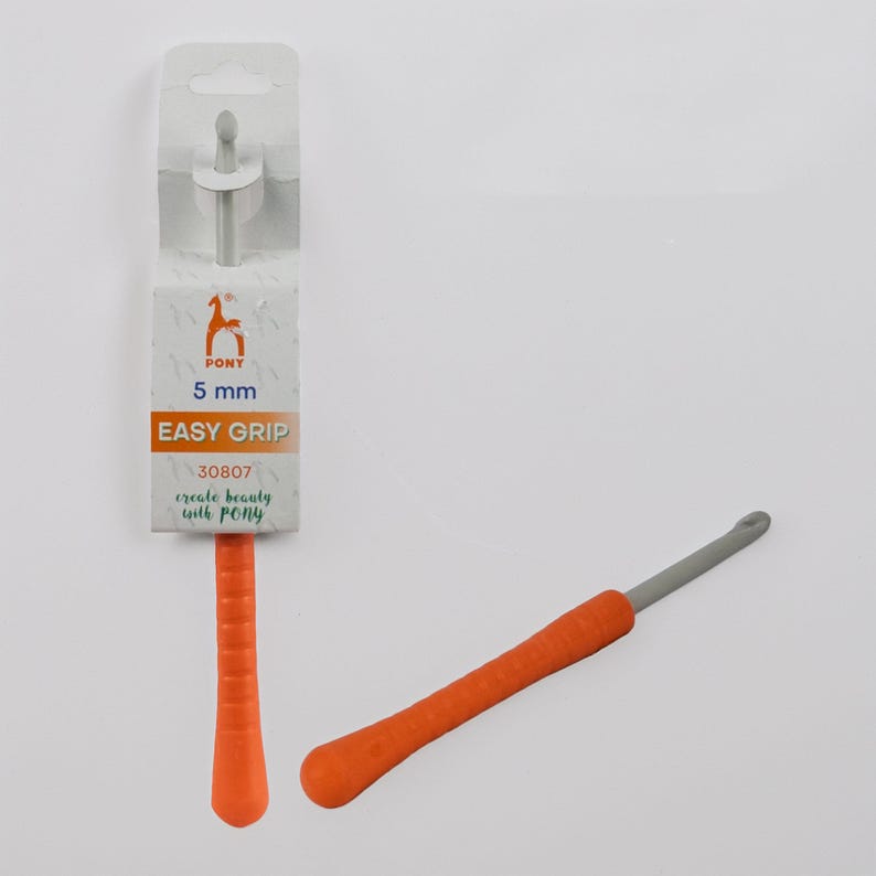 May include: An orange and gray crochet hook with an easy grip handle. The packaging shows the brand "PONY" and the text "5 mm EASY GRIP". The hook is designed for creating beauty with PONY.