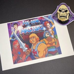 May include: A vintage He-Man and the Masters of the Universe print featuring He-Man, Teela, Man-At-Arms, and Beast Man. The print is on a white background with a purple, blue, and black starry sky.