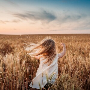 May include: A young girl with long blonde hair runs through a field of golden wheat at sunset. Her white dress billows behind her as she spins around.