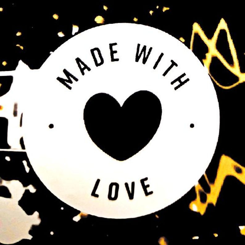 May include: A circular white label featuring a black heart icon in the center. The text MADE WITH LOVE is printed in black capital letters around the heart. The background is black with abstract yellow and white paint splatter patterns.