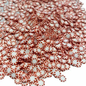 May include: A large pile of white and red candy sprinkles shaped like peppermint candies.