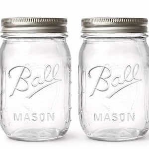 May include: Two clear glass Ball Mason jars with silver lids. The jars have the Ball logo and the word "MASON" embossed on the front. The jars are empty and ready for use. Perfect for canning, storage, or decoration.