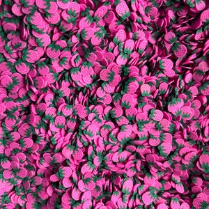 May include: A large pile of pink and green pineapple-shaped sprinkles. The sprinkles are perfect for decorating cakes, cupcakes, and other desserts.