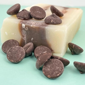 May include: A bar of soap with a swirl of brown and white, surrounded by chocolate chips.