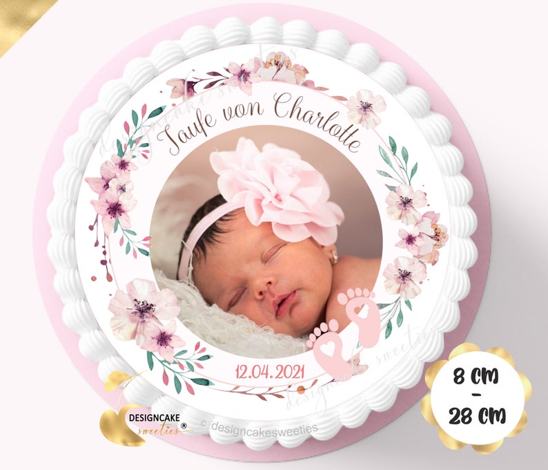 May include: A white cake with a pink and green floral design and a photo of a baby girl in the center. The cake is decorated with the text "Taufe von Charlotte" and the date "12.04.2021". The cake is 8 inches in diameter and 28 inches in circumference.